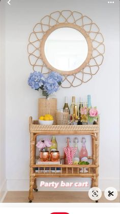 a party bar cart with flowers and bottles on the top, in front of a round mirror