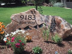 a large rock sitting in the middle of a flower garden