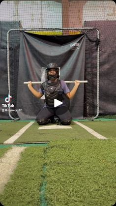 a baseball player squats on the field with his bat