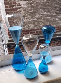 three blue and clear sandglasses sitting on a window sill