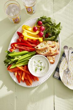 a white plate topped with meat and veggies next to two glasses of water