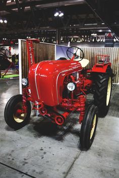 an old red tractor parked in a garage