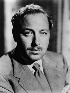 a black and white photo of a man in a suit with a moustache on his face