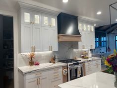 a kitchen with marble counter tops and white cabinets, along with an island in the middle