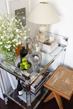 a glass table topped with lots of bottles and glasses next to a vase filled with flowers