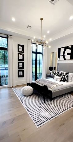 a modern bedroom with black and white decor on the walls, wood flooring and large windows