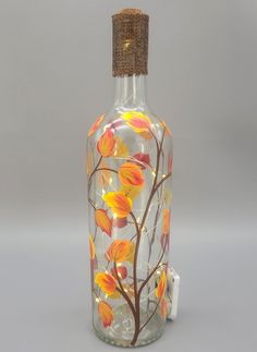 a glass bottle with flowers painted on the side and a corked top is sitting in front of a gray background