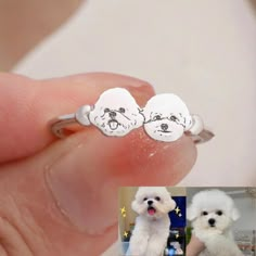 two small white dogs sitting on top of each other's earrings in their hands