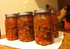 four jars filled with food sitting on top of a counter next to a tea towel