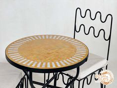 a table and two chairs sitting next to each other on a white surface with a black iron frame