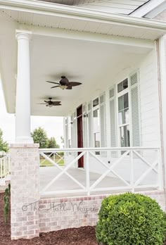 a porch with white pillars and ceiling fans