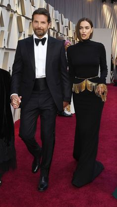 a man and woman walking on the red carpet at an oscars event in black outfits