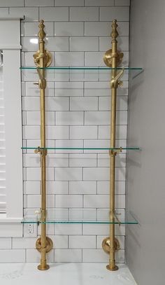 two glass shelves with brass fixtures in a bathroom