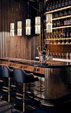 a bar with several stools and bottles on the wall behind it in a dimly lit room