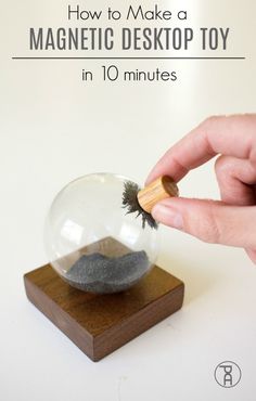 a hand holding a wooden stick over a glass ball with sand inside it and the words how to make a magnetic desktop toy in 10 minutes