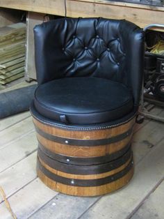 a black leather chair sitting on top of a wooden barrel