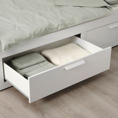 a bed with two drawers underneath it and a blanket on the bottom one drawer is open