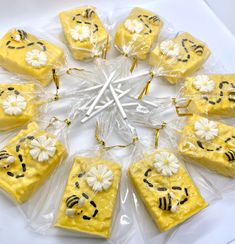 eight pieces of yellow cake with white flowers and bees on them in cellophane bags