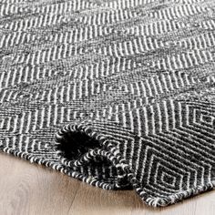 an area rug that has been placed on top of a wooden floor with a black and white pattern