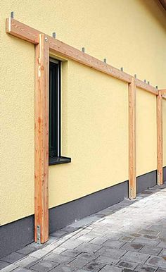 a fire hydrant sitting in front of a yellow building with wooden posts on the side