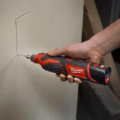 a man is using a drill to fix a hole in the wall with a screwdriver