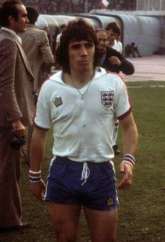 a man standing on top of a soccer field wearing shorts and a white t - shirt