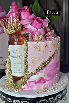 a pink and gold cake sitting on top of a table next to a bottle of wine