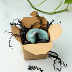 two donuts in a cardboard box with black sprinkles on the table