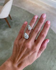 a woman's hand with two engagement rings on her left and the middle finger