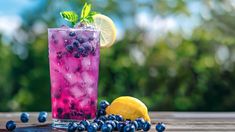 a glass filled with blueberries and lemon on top of a wooden table