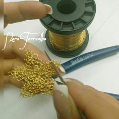 a person is working on some gold chain with scissors and wire spools next to the spool