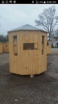 a wooden outhouse sitting in the middle of a parking lot with no doors on it