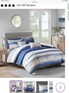 a bed with blue and white striped comforter set on top of it, in front of a window