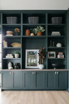 an open bookcase filled with lots of books next to a potted plant on top of a wooden table