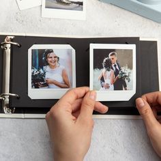 a person holding an open photo album with two pictures on it