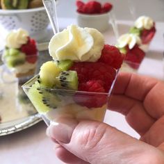 a person holding up a piece of fruit in front of other desserts on the table