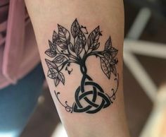 a tattoo on the arm of a woman with a tree and celtic knot around it