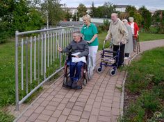 an elderly man in a wheel chair being guided by two women