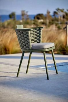 a chair sitting on top of a cement floor next to a swimming pool and grass