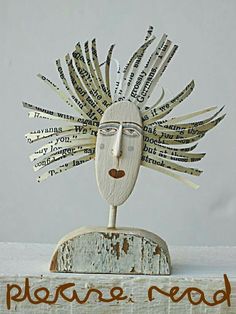 a wooden sculpture with words written all over it and a face made out of newspaper strips