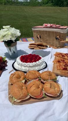 sandwiches and desserts on a picnic table with flowers in the backgrouf