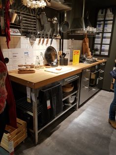 a kitchen with lots of pots and pans hanging from the ceiling, next to a woman standing in front of an oven