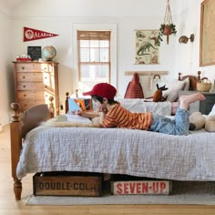 a young boy laying on top of a bed in a room with wooden floors and white walls