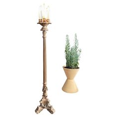 a tall metal pole with a potted plant on it and a candle holder next to it