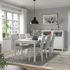 a dining room table surrounded by chairs in front of a window