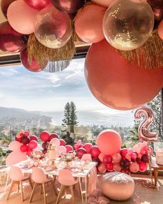 balloons are hanging from the ceiling above a table with pink and red decorations on it