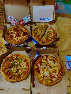 four pizzas in boxes on a table