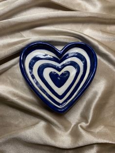 a blue and white heart shaped dish sitting on top of a satin cloth covered table