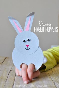 a child's hand holding up a paper bunny puppet with the words bunny finger puppets on it