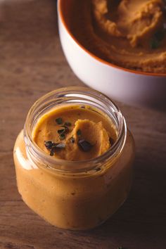 a jar filled with hummus sitting on top of a wooden table